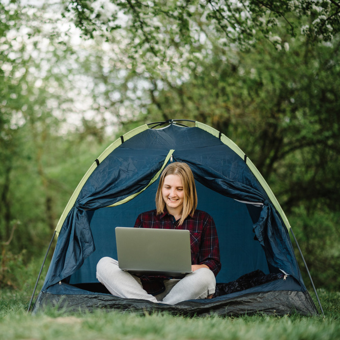 Writer in tent on computer in the woods